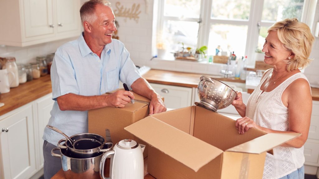 Two people are unpacking boxes in a kitchen