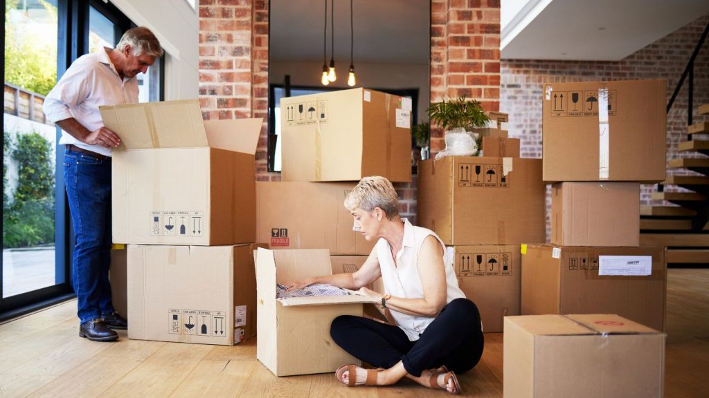Two people sitting on the floor in front of boxes